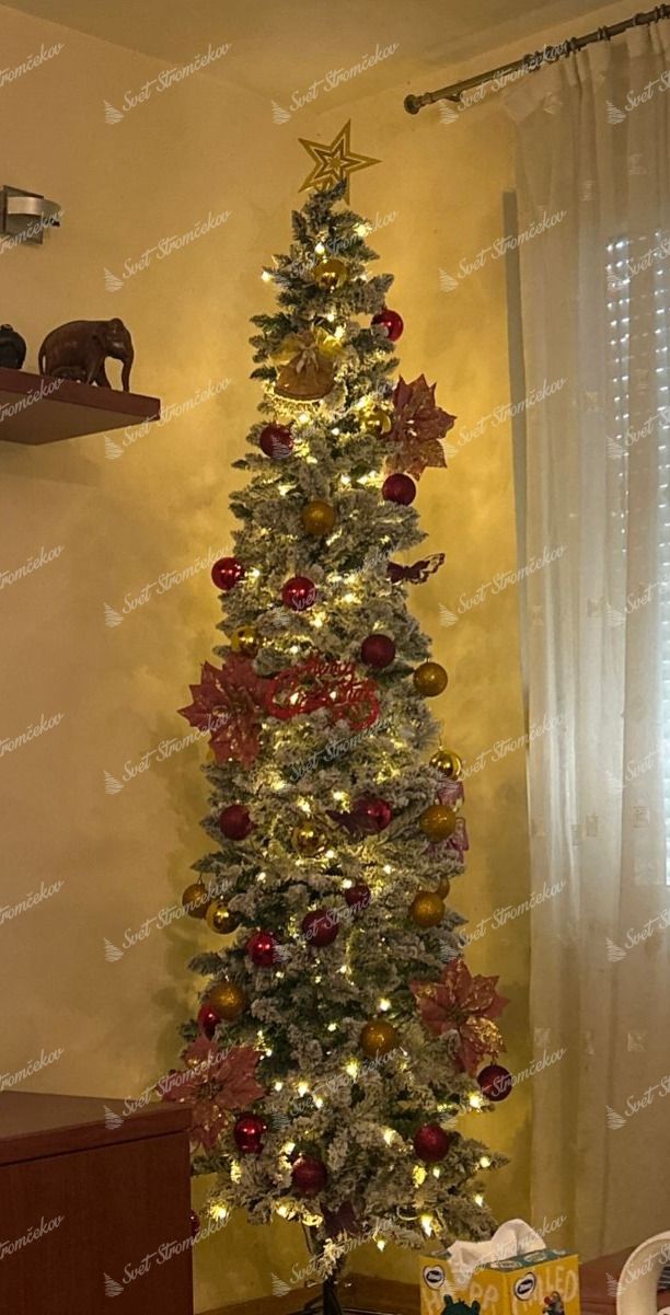 Umelý vianočný stromček Smrek Biely Štíhly 240cm LED480 je ozdobený červenými a zlatými vianočnými guľami a vianočnými ružami.