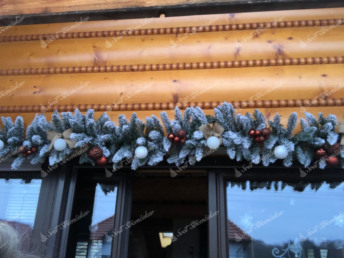 Vianočná girlanda zasnežená 270cm na okne, ozdobená medenými a bielymi vianočnými guľami a jutovými mašľami.