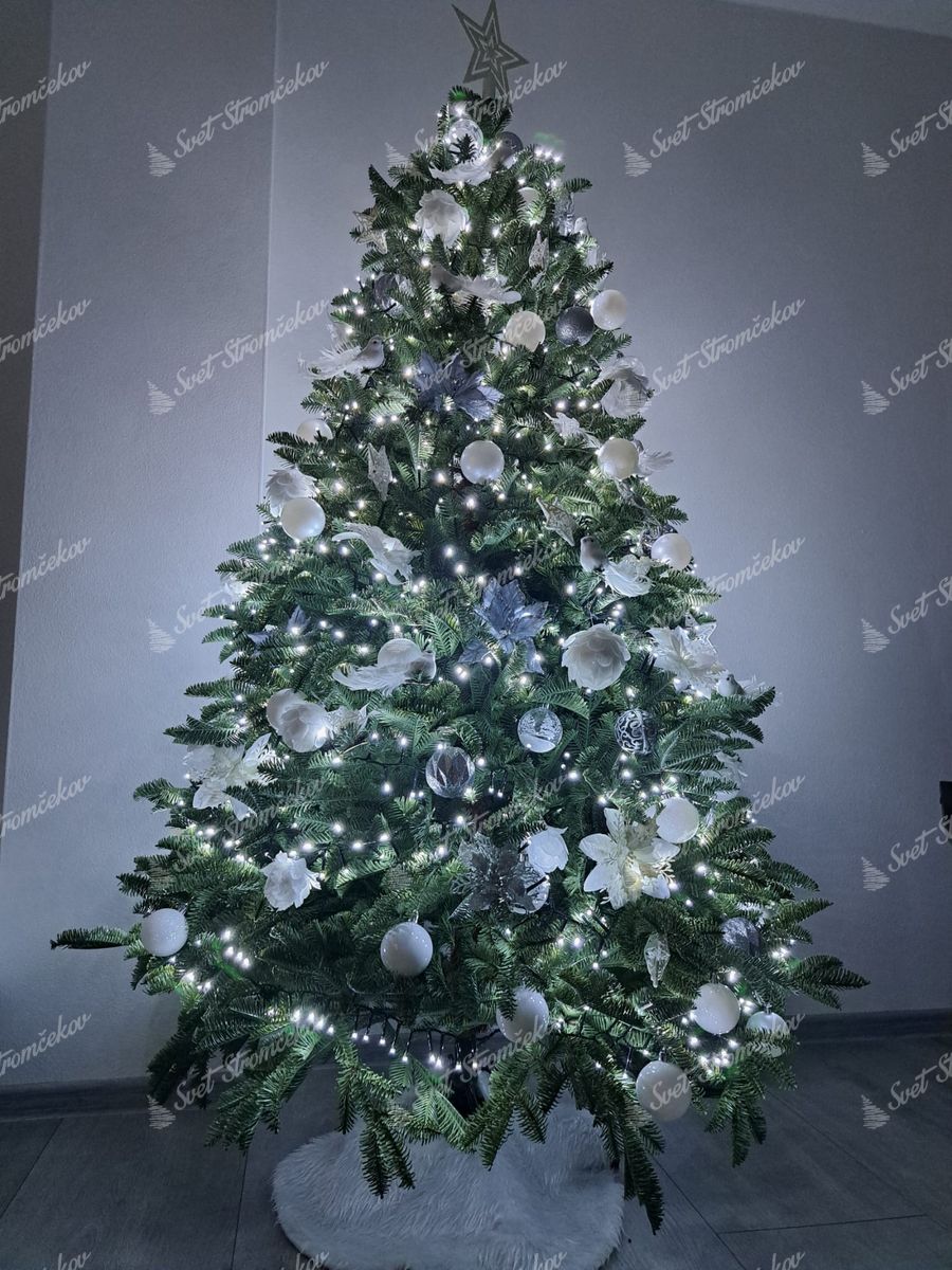 Vianočný stromček 3D Jedľa Pôvabná 180cm je ozdobený bielymi a striebornými vianočnými guľami a vianočnými ružami.