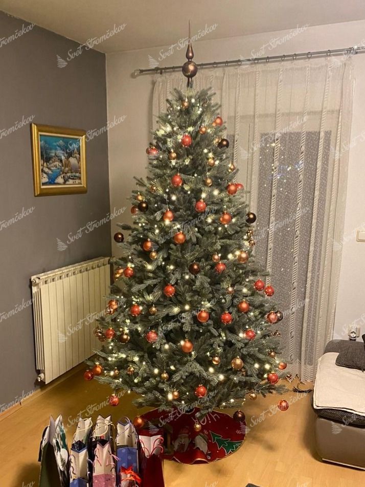 Vianočný stromček FULL 3D Smrek Ľadový 210cm je husto ozdobený červenými a zlatými vianočnými guľami.